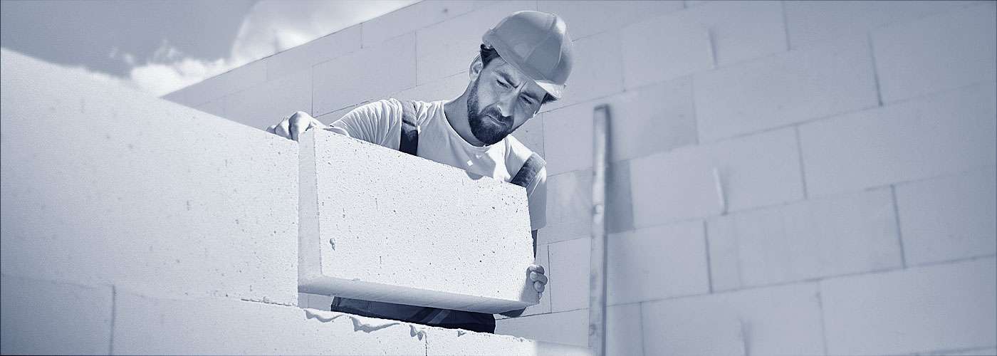 Ein Maurer auf einer Großbaustelle mit Gasbetonsteinen.