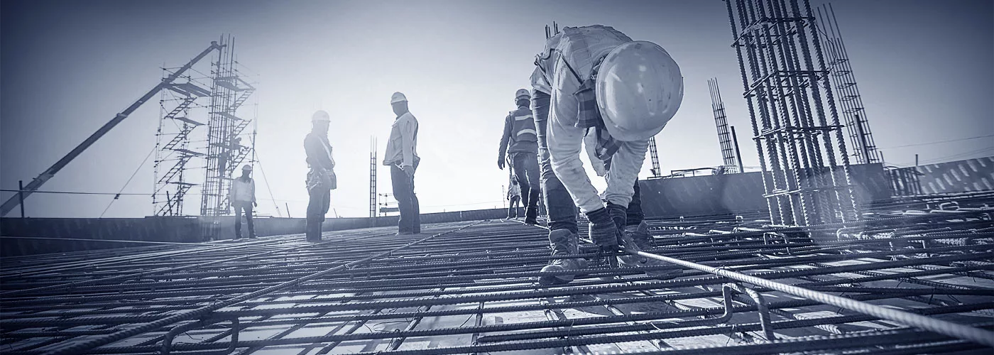 Eisenflechter bei der Arbeit an einem Dach. Im Hintergrund steht ein Gerüst.