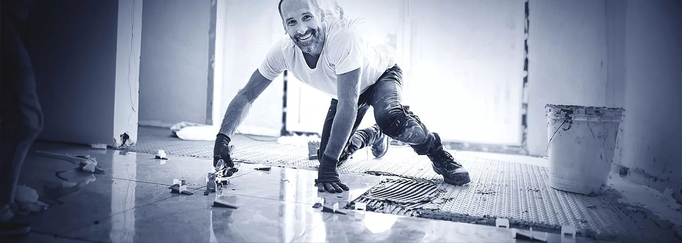 Ein Fliesenleger lachend bei der Arbeit.