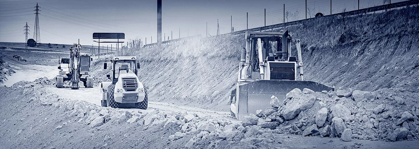 Drei Baustellenfahrzeuge auf einer Baustelle.