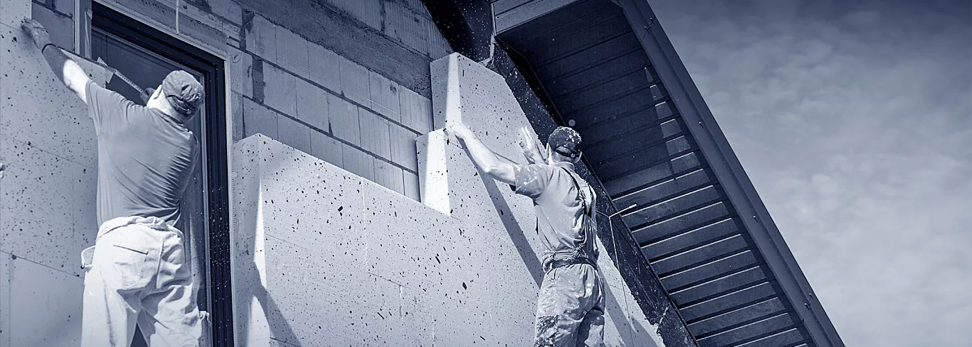 Zwei Monteure arbeiten an der Fertigstellung einer Außenwand eines Hauses.