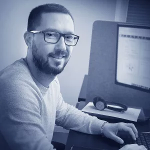 Hani Hammoud sitzt an seinem Arbeitsplatz im Finanzwesen der W&W Personaleinsatz GmbH. Er blickt freundlich von seiner Tätigkeit am Bildschirm auf und wendet seinen Kopf zum Betrachter, während er auf der Tastatur weiterarbeitet.