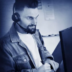 Marcel Klingenberg telefoniert mit Headset an seinem Arbeitsplatz in der Kundenberatung der W&W Personaleinsatz GmbH. Er blickt konzentriert auf seinen Monitor und macht sich Notizen.